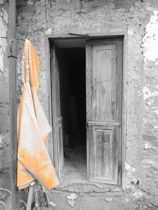 Dans la via Guglielmi, une tenue de pêcheur mise à sécher - Teinte orangée et modernité de l'habit qui tranche avec les vieilles pierres et la porte délabrée.